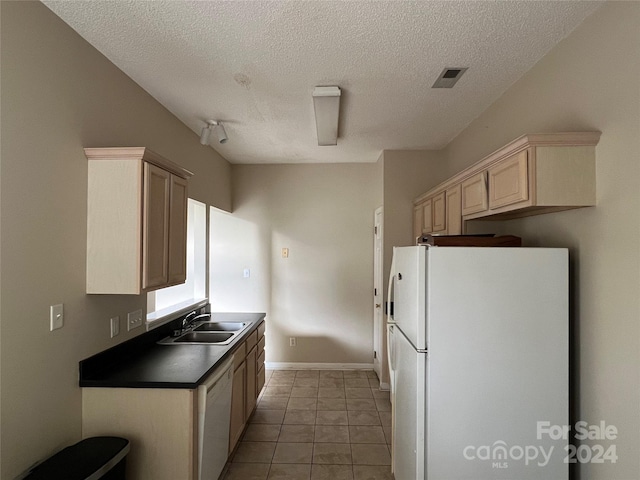 kitchen with a textured ceiling, sink, light tile patterned floors, and white appliances