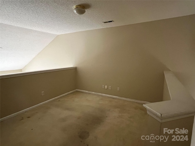 bonus room featuring lofted ceiling, light colored carpet, and a textured ceiling