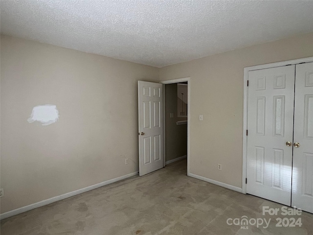 unfurnished bedroom with a closet, light carpet, and a textured ceiling