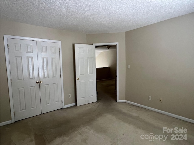 unfurnished bedroom featuring a textured ceiling, carpet flooring, and a closet