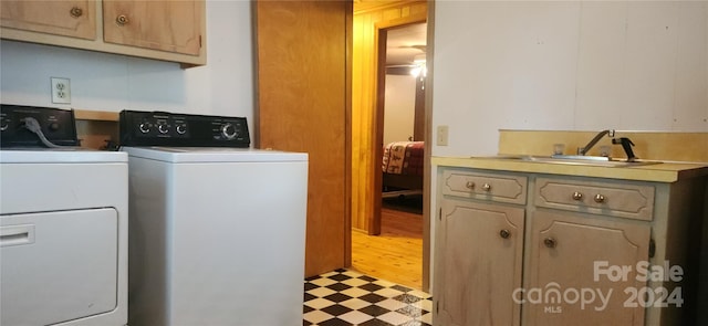 laundry area featuring cabinets, washer and clothes dryer, sink, and light hardwood / wood-style floors