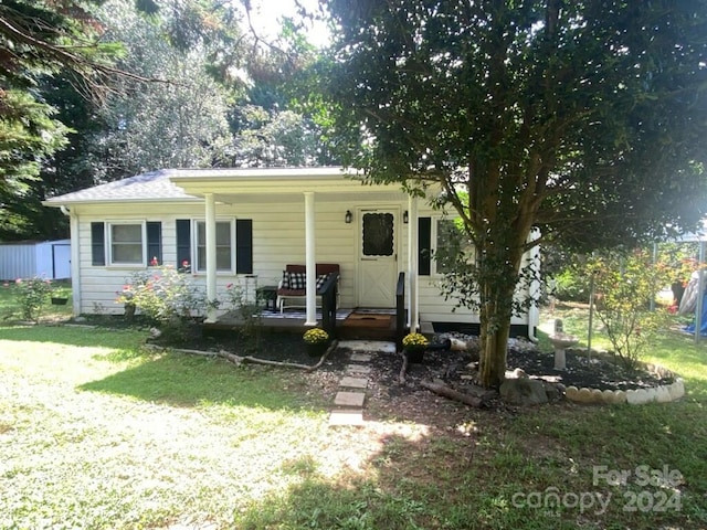 rear view of house featuring a yard and covered porch