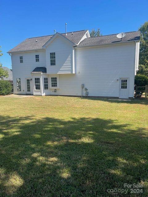 rear view of property featuring a lawn