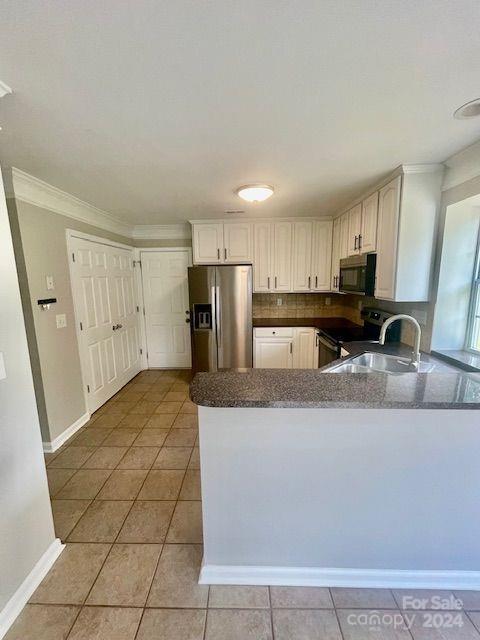 kitchen with ornamental molding, stainless steel appliances, kitchen peninsula, and sink