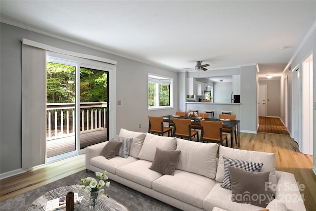 living room featuring light wood-type flooring, ornamental molding, and ceiling fan