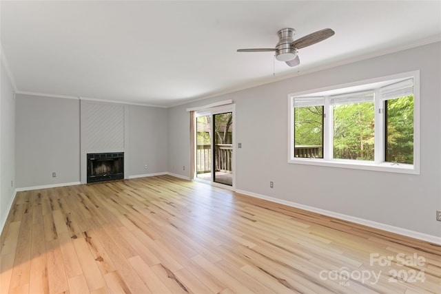 unfurnished living room featuring a fireplace, light wood-type flooring, ornamental molding, and ceiling fan