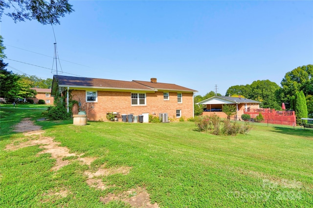 rear view of house with a yard and central AC