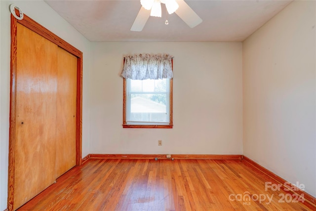 unfurnished bedroom featuring ceiling fan, a closet, and light wood-type flooring