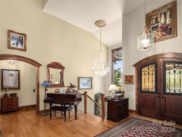 entrance foyer featuring french doors, light hardwood / wood-style flooring, a chandelier, and lofted ceiling