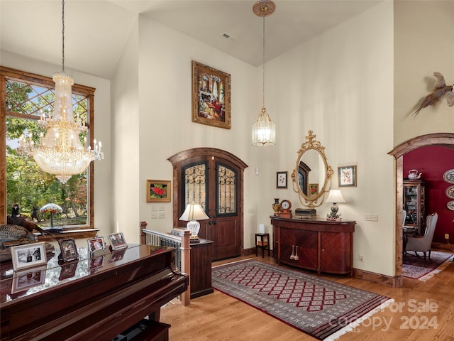 entrance foyer with light hardwood / wood-style flooring, a high ceiling, and an inviting chandelier