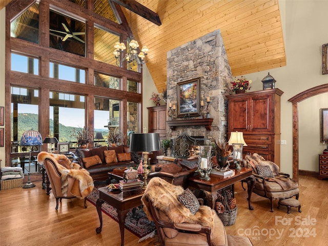 living room with high vaulted ceiling, a fireplace, wooden ceiling, beam ceiling, and light hardwood / wood-style flooring