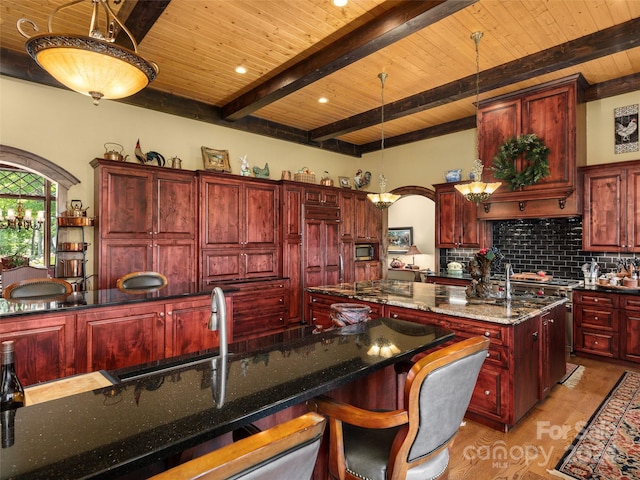 85 Smokey Ridge Trl, Arden, NC 28704 - kitchen featuring reddish brown cabinets, wood ceiling with exposed beams, an island with sink, backsplash, and light wood-style flooring