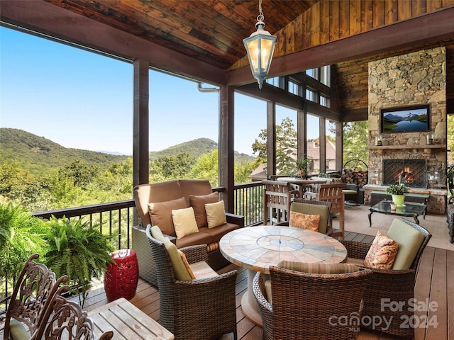 sunroom / solarium with vaulted ceiling, wooden ceiling, and an outdoor stone fireplace