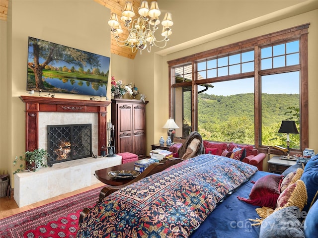 bedroom featuring multiple windows, wood-type flooring, a fireplace, and an inviting chandelier