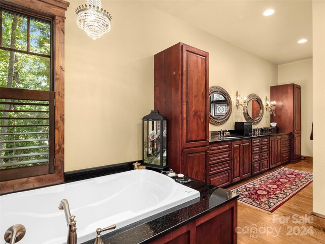 bathroom featuring hardwood / wood-style flooring, a bathing tub, vanity, and a wealth of natural light