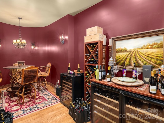 wine room featuring a notable chandelier, wine cooler, and hardwood / wood-style floors