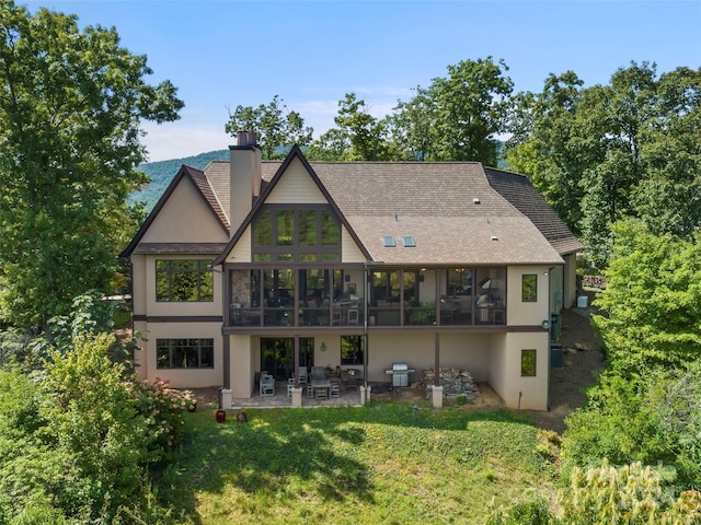 85 Smokey Ridge Trl, Arden, NC 28704 - rear view of house featuring a patio, stucco siding, a sunroom, a shingled roof, and a lawn