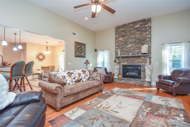 living room with light hardwood / wood-style flooring, a fireplace, high vaulted ceiling, and ceiling fan