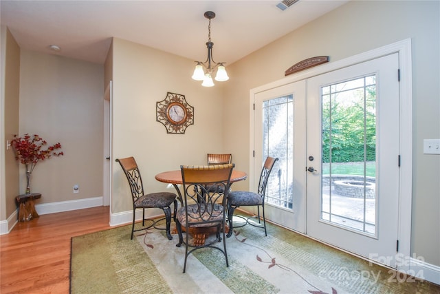 dining area with french doors, a notable chandelier, and hardwood / wood-style flooring