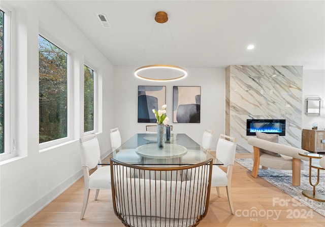 dining room with a fireplace, a healthy amount of sunlight, and light wood-type flooring