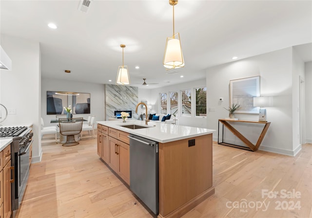 kitchen featuring sink, ceiling fan, an island with sink, appliances with stainless steel finishes, and light hardwood / wood-style floors