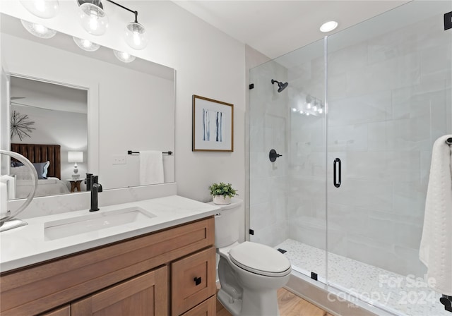 bathroom featuring hardwood / wood-style flooring, vanity, toilet, and a shower with shower door