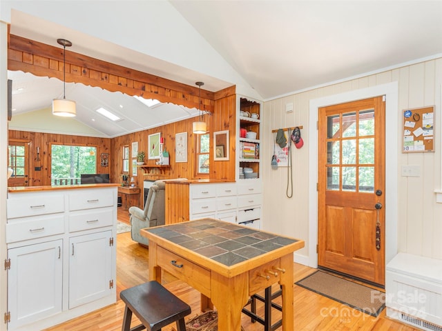 kitchen with decorative light fixtures, white cabinets, a wealth of natural light, and light hardwood / wood-style floors