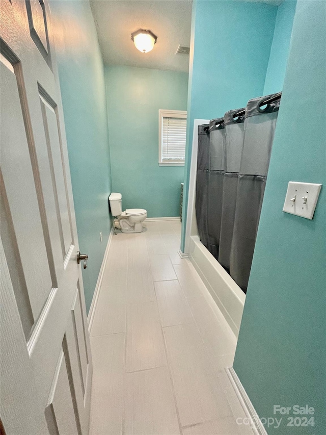 bathroom featuring a shower with shower curtain, tile patterned flooring, and toilet