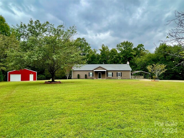 single story home featuring a garage, a front yard, and an outbuilding