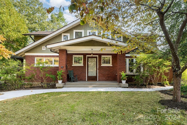 view of front of house with a front yard, brick siding, and covered porch