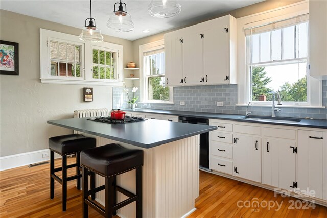 kitchen featuring white cabinetry, decorative light fixtures, sink, a breakfast bar, and light hardwood / wood-style floors