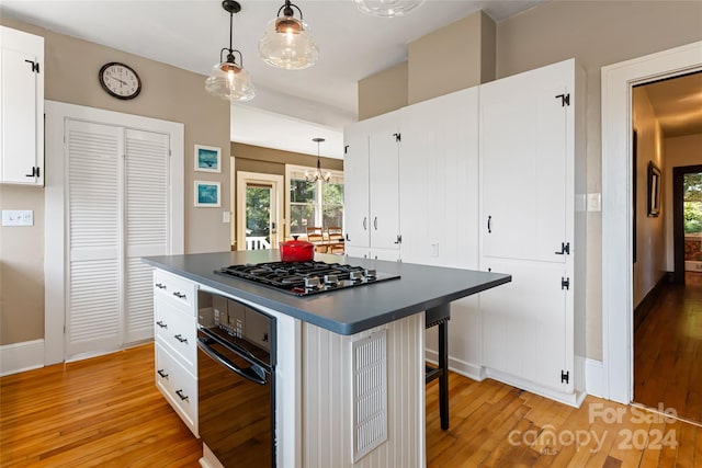 kitchen featuring pendant lighting, stainless steel gas cooktop, light hardwood / wood-style flooring, a kitchen breakfast bar, and white cabinets