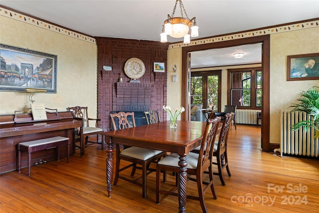 dining area with radiator, a chandelier, and hardwood / wood-style flooring