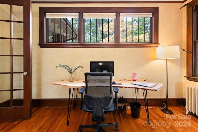 office space with radiator heating unit, wood finished floors, and baseboards