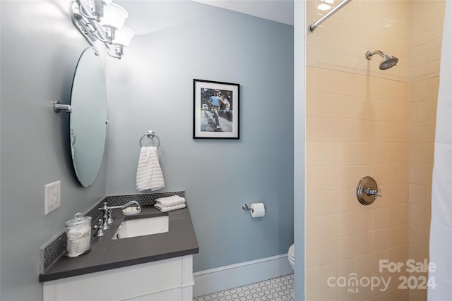 full bathroom with tiled shower, vanity, baseboards, and toilet