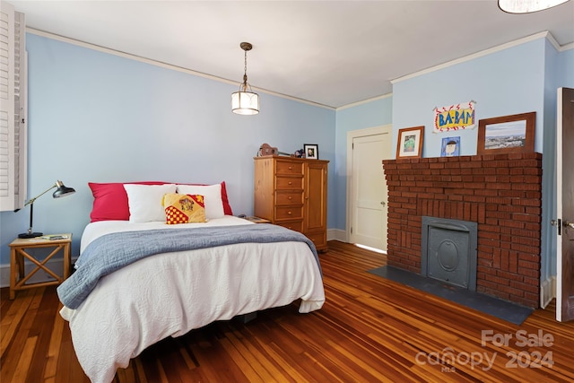 bedroom featuring a fireplace, dark hardwood / wood-style floors, and crown molding