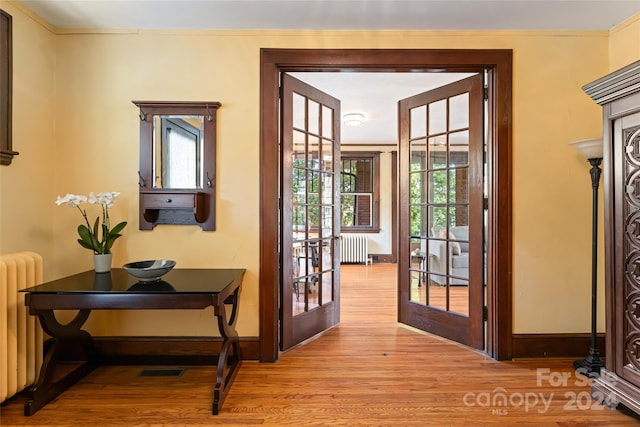 doorway to outside with radiator, wood finished floors, and ornamental molding