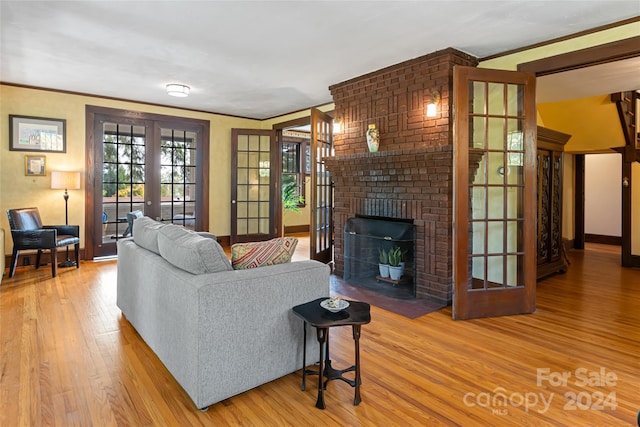 living room with baseboards, ornamental molding, french doors, a brick fireplace, and wood finished floors