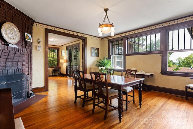 dining room featuring hardwood / wood-style flooring, radiator, and a brick fireplace