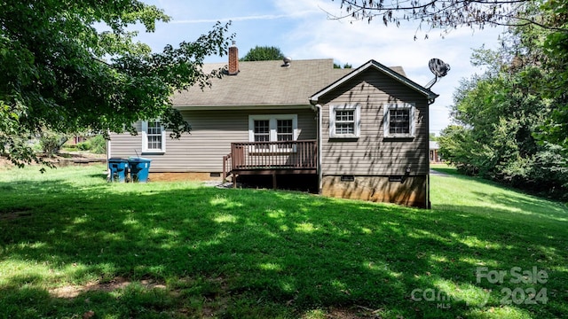 rear view of house with a wooden deck and a lawn