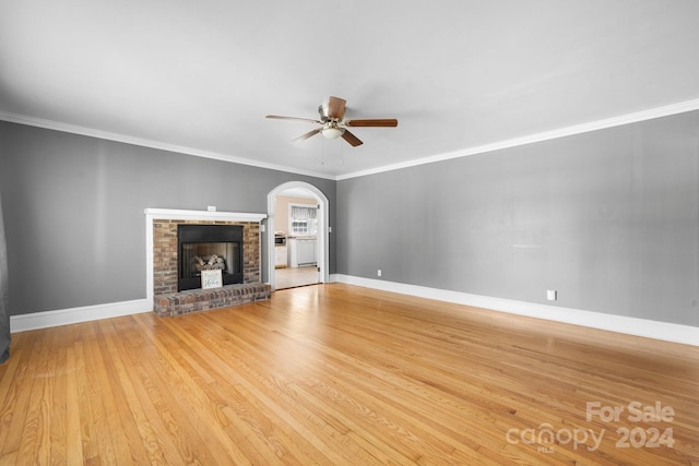 unfurnished living room featuring ceiling fan, a fireplace, crown molding, and wood-type flooring