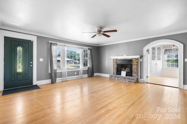 unfurnished living room with plenty of natural light, ceiling fan, a brick fireplace, and light hardwood / wood-style floors