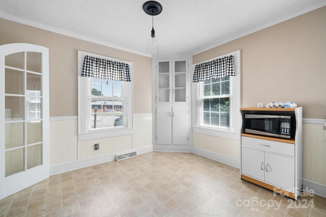 unfurnished dining area featuring ornamental molding and a textured ceiling