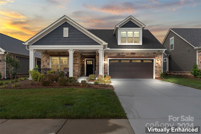 view of front of home featuring a yard, covered porch, and a garage