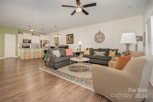 living room with ceiling fan with notable chandelier and wood-type flooring