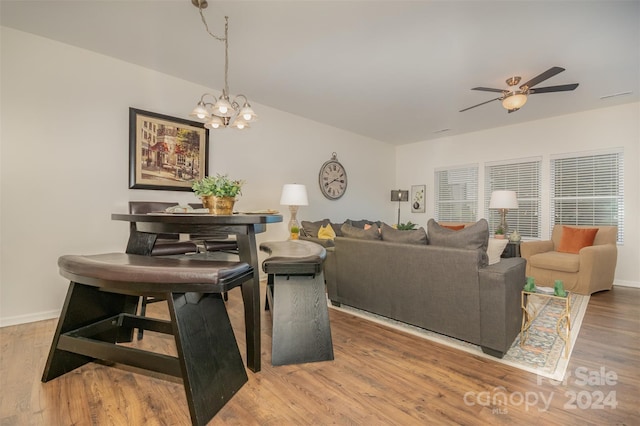 living room with ceiling fan with notable chandelier and hardwood / wood-style flooring