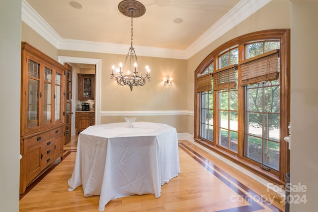 dining room with crown molding, light hardwood / wood-style floors, and a chandelier