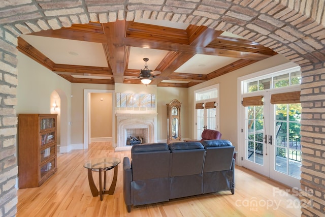 living room featuring light hardwood / wood-style floors, beamed ceiling, coffered ceiling, ceiling fan, and french doors