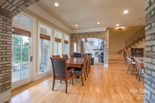 dining space featuring ornamental molding, light hardwood / wood-style floors, and a fireplace