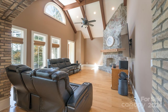 living room with beamed ceiling, a fireplace, light hardwood / wood-style flooring, high vaulted ceiling, and ceiling fan